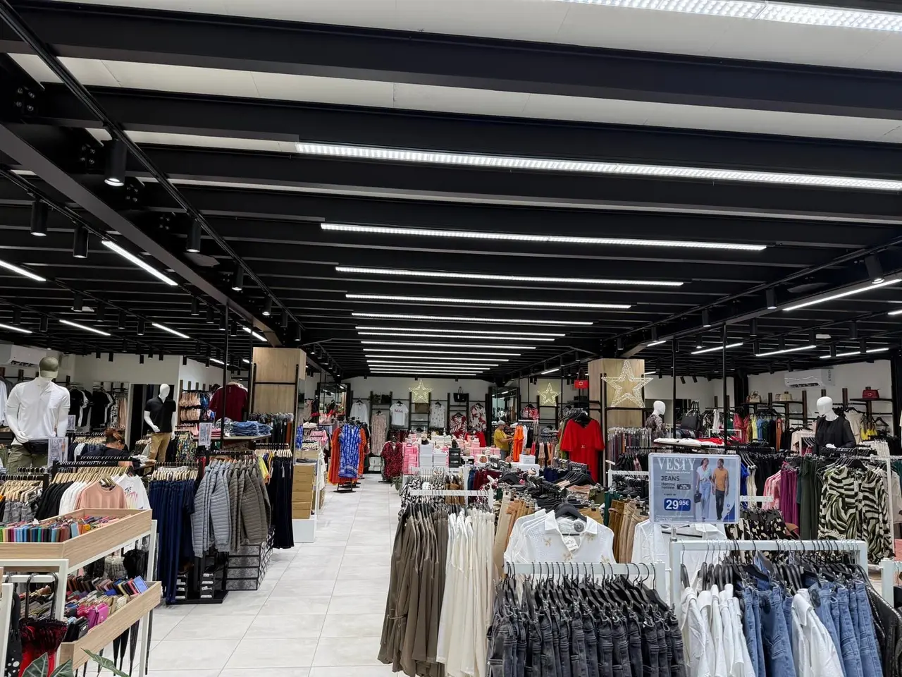 Clothing sales floor under a public-access mezzanine with a black structure
