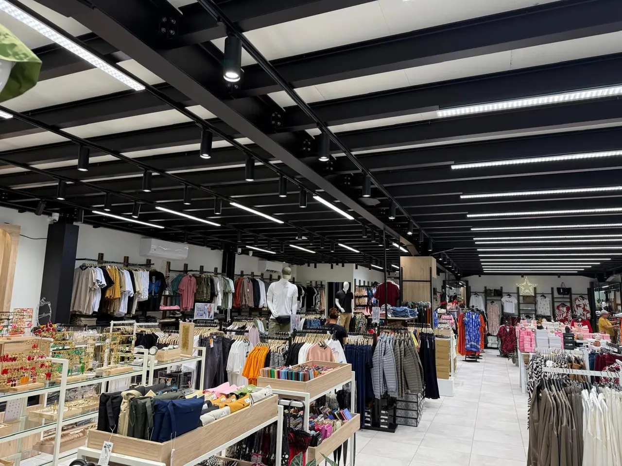 Shop fitted out under a public-access mezzanine, with black steel beams and integrated lighting