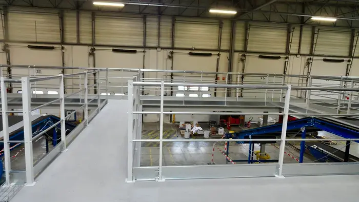 Passerelles et mezzanine intégrées au-dessus de lignes de convoyeurs dans un centre de tri