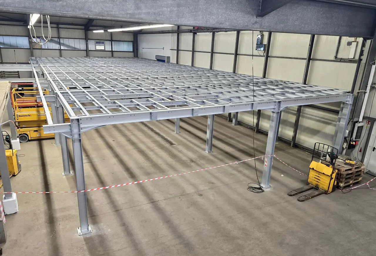 Steel frame of a warehouse mezzanine being assembled, with a forklift