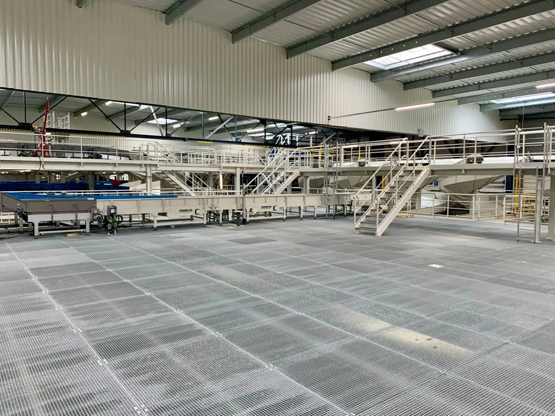 Grating walkway with guardrails above the installations of a warehouse