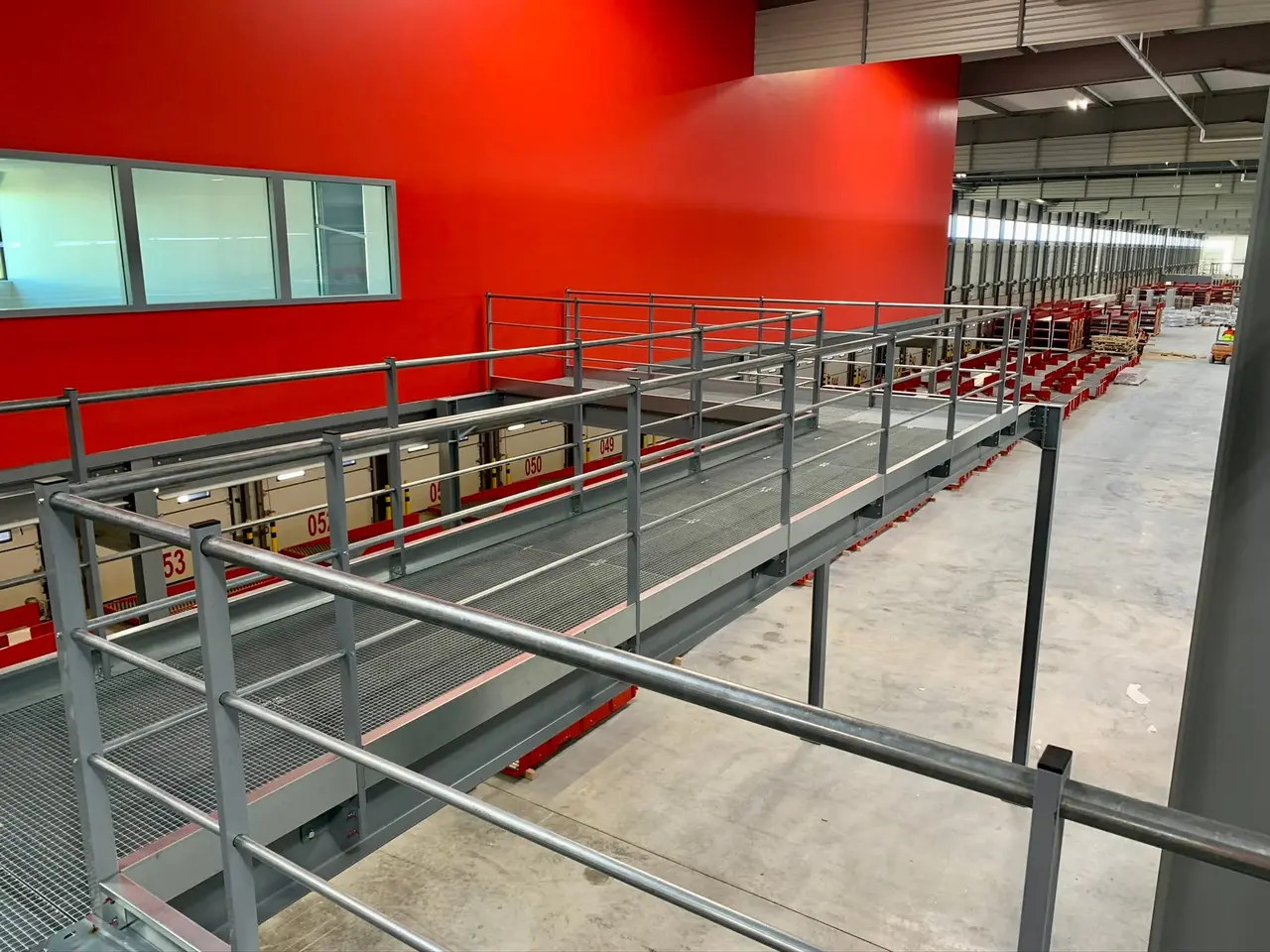 Steel walkway with guardrails running alongside the conveyors of a logistics site