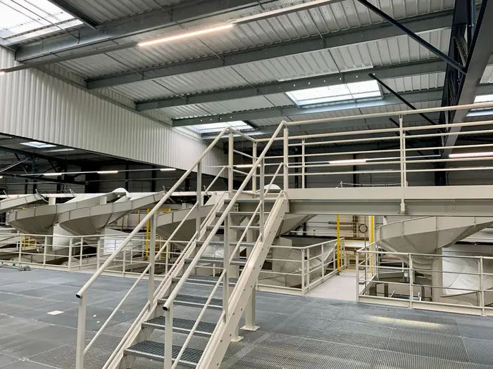 Two-level steel platform with stairs and guardrails around sorting equipment