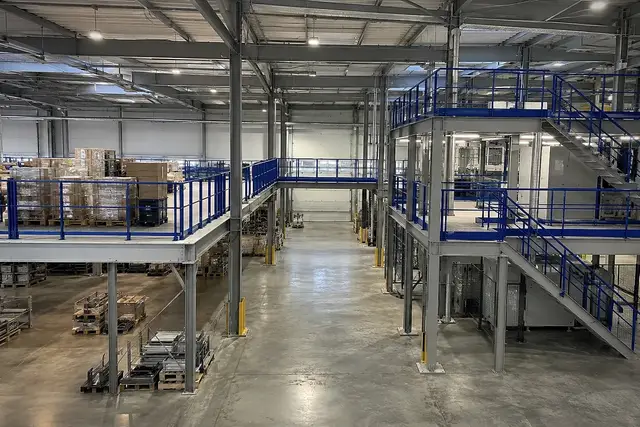 Storage mezzanine, walkway and two-level platform with blue guardrails in a factory