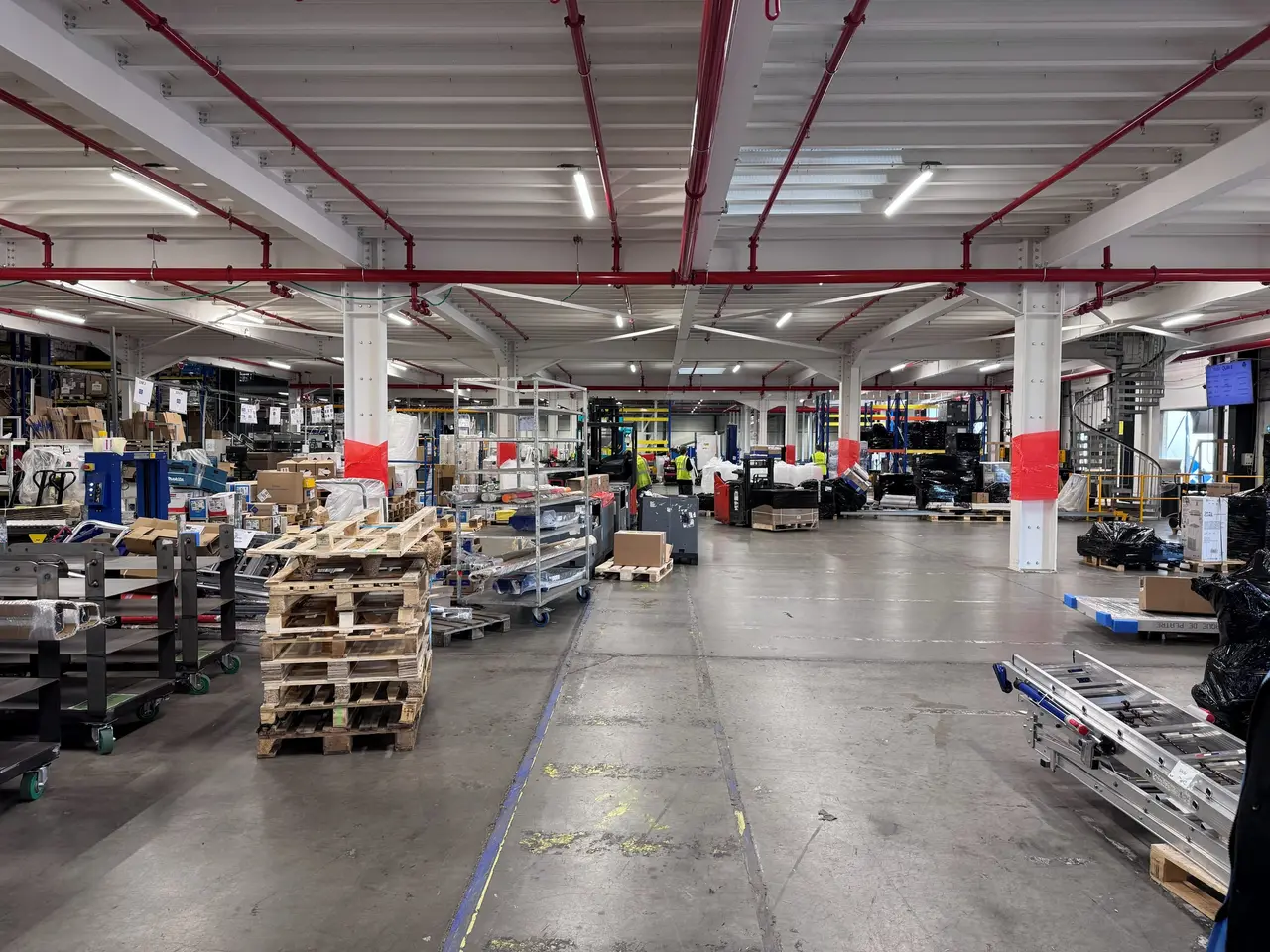 Workshop under a steel mezzanine, with red beams and widely spaced columns